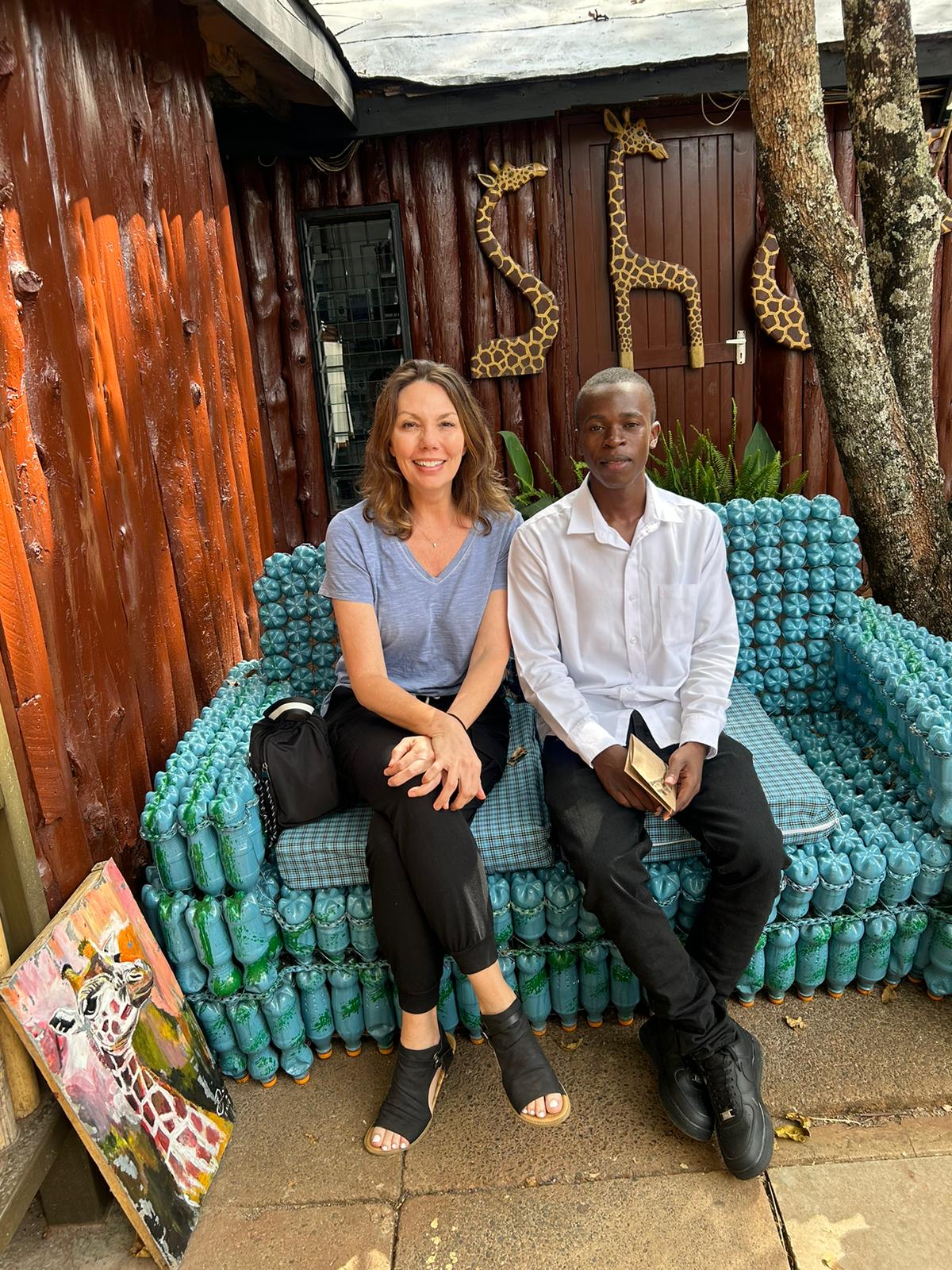 John seated with a traveller at the Giraffe Centre